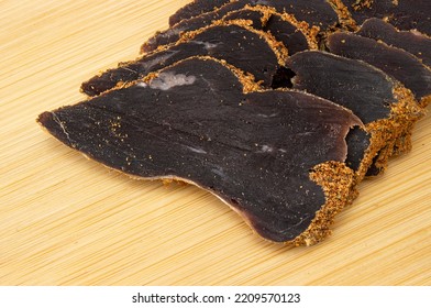 Close-up Sliced Venison Jerky On Wooden Board. Dried Deer Meat Snack. Top View