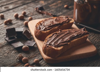 Closeup slices of bread with chocolate hazelnut cream on wooden background.
