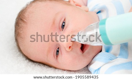 Closeup slow motion of cleaning tiny nose of newborn baby with electric aspirator. Concept of babies and newborn hygiene and healthcare. Caring parents with little children