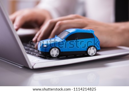 Close-up Of A Small Blue Car On Laptop Keypad