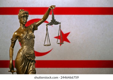 Close-up of a small bronze statuette of Lady Justice before a flag of Northern Cyprus.