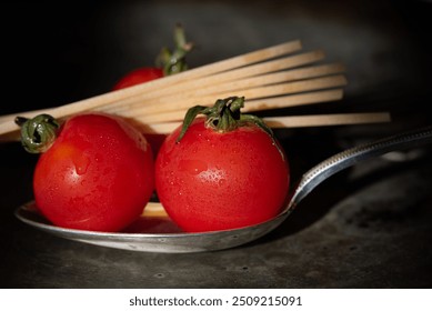 Close-up of small cherry tomatoes lying on a silver spoon. Spaghetti in the background, also on the spoon. The ingredients for Italian pasta against a grey background. - Powered by Shutterstock