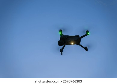 Close-up of a small glowing drone hovering in the evening.
