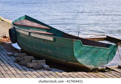 Closeup of a small green rowboat on the shore of the lake