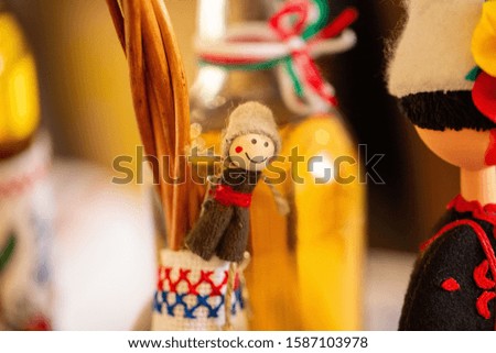 A closeup of a small handmade smiling doll surrounded by handmade toys with a blurry background