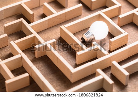 Closeup small light bulb in the maze game built by wood blocks, finding the right way to the success, searching creative idea concept
