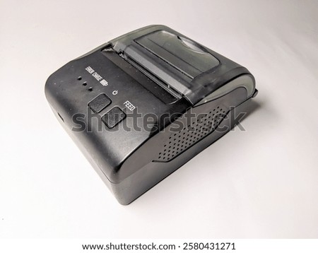 Close-up of a small mobile receipt printer on a clean white surface. Sleek and functional design for fast and easy thermal printing.