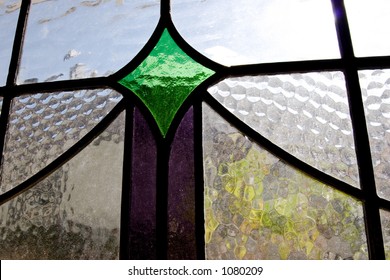 Closeup Of A Small Stained Glass Window With Green And Purple Sections