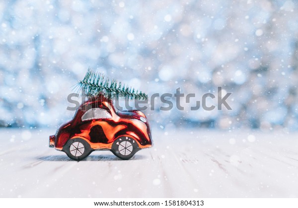 Close-up of a small toy car\
carries a xmas tree on the roof, concept Christmas and New\
Year