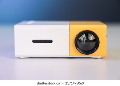 A closeup of a small yellow color Mini Projector on  white table, it's a budget Chinese pocket projector. Made for fun and entertainment.