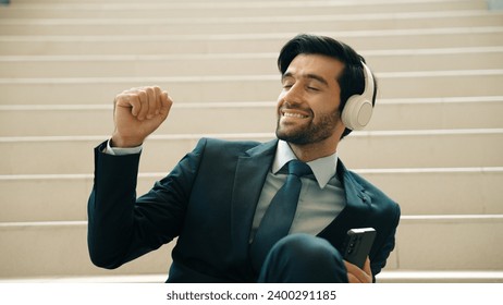 Closeup of smart business man listening and enjoy music while wear headphone. Project manager smiling while getting good news, getting promotion, increasing sales. Relaxing man enjoy music. Exultant. - Powered by Shutterstock