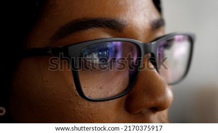Close-up of a smart business woman wearing computer glasses looking at a computer screen, using the Internet, reading information, watching, working on the Internet.