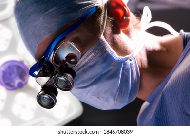 A closeup of a smart and confident surgeon performing an operation while looking through an advanced surgical loupe in a modern operating room
