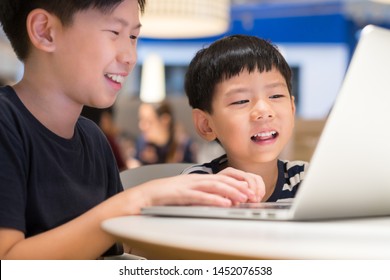 Closeup: Smart looking asian boys brother searching, studying playing with online media from laptop computer. Kids, E-learning, Gamification, Coding, Social media, Online Technology Education concept.