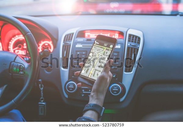 Closeup
of smartphone in hand of girl sitting behind the wheel of modern
car. Young woman uses digital gadget. Girl paves way to browser. On
screen of smartphone map of area. Cropped
image