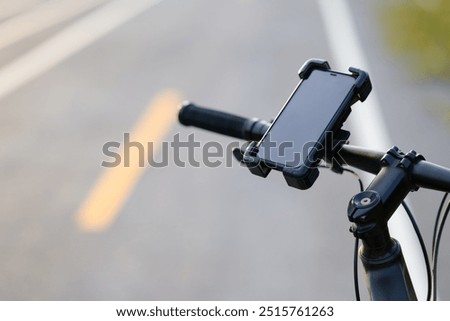 Closeup smartphone in a quick release attached on the handlebar of a bicycle while parking on the roadside