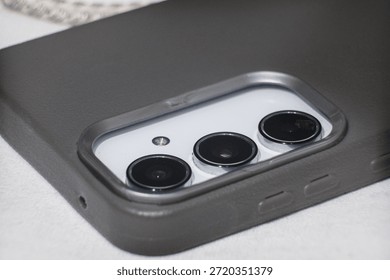 Close-up of a smartphone triple camera module in a protective case, highlighting modern technology and sleek design.