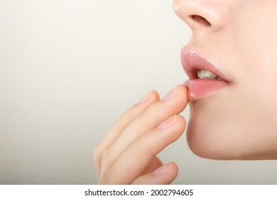 Close-up of smiling beauty model's  lips.. Beautiful young woman with perfect skin touches her lips.. Spa and Wellness, Skin Care Concept. Selective foocus.