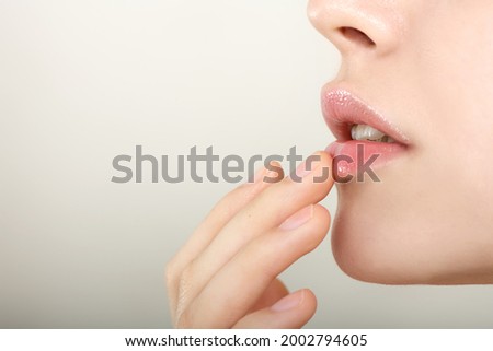 Close-up of smiling beauty model's  lips.. Beautiful young woman with perfect skin touches her lips.. Spa and Wellness, Skin Care Concept. Selective foocus.
