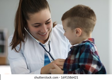 Close-up Of Smiling Doctor Examine Child Lugs. Lovely Female Doctor In Medical Gown Wearing Stethoscope. Modern Medicine And Pediatric Appointment Concept