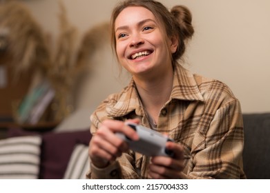 Close-up. Smiling girl gamer plays a video game with a joystick in her hands. Fun pastime, online games with friends, virtual reality, youth culture, game strategy, cyberspace.