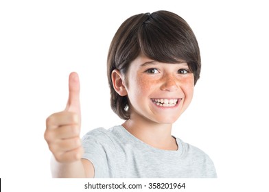 Closeup Of Smiling Little Boy Showing Thumb Up Gesture Isolated On White Background. Portrait Of Happy Cute Boy Showing Thumb Up And Looking At Camera. Kid Giving You Thumbs Up.
