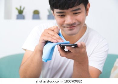 Closeup Of Smiling Man Cleaning Phone Screen By Sanitizer.