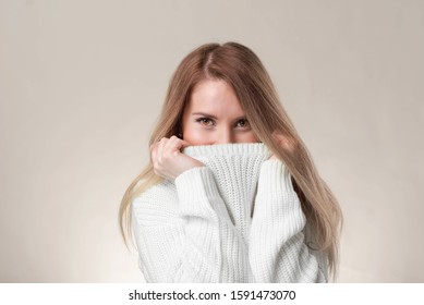 Close-up smiling pretty european, brown hair, pull sweater on face and smiling with eyes, playfully and flirty giggle, gazing camera, standing white background silly.
