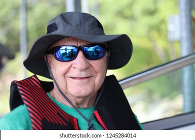 Closeup smiling senior man wearing reflective sunglasses and hat. Ready for boat outing 