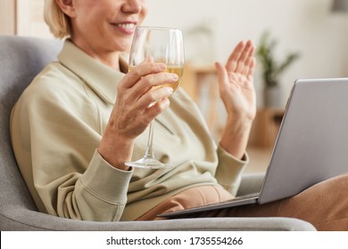 Close-up Of Smiling Woman Drinking Wine And Talking Online With Her Friend Using Laptop At Home