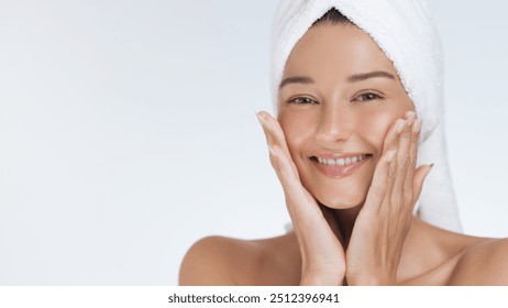 Close-up of a smiling woman with a towel turban, gently touching her face after a refreshing skincare routine. Ideal for promoting beauty, skincare, wellness, and self-care products and campaigns. - Powered by Shutterstock