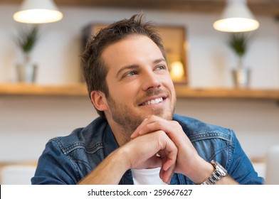 Closeup of smiling young businessman thinking in office 