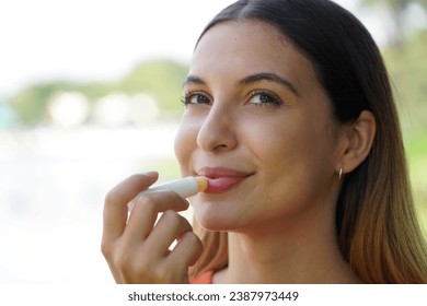 Close-up of smiling young woman applying sun protection on her lip outdoor - Powered by Shutterstock