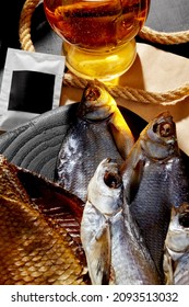 Closeup Of Smoked And Salted Dried Fish Served To Amber Lager On Black Wooden Board