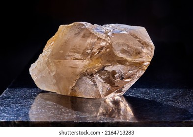 Close-up Of Smoky Quartz Stone On Dark Polished Slab. Rauchtopaz Crystal On Black Background. Texture Of Transparent Quartz Crystal.