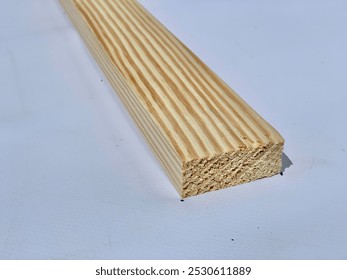 A close-up of a smooth, rectangular wooden plank with visible grain patterns running along its surface. The light-colored wood contrasts against the plain white background, highlighting the texture. - Powered by Shutterstock