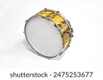 Close-up of a snare drum with a golden shell and white drumhead, highlighting its shiny surface and intricate hardware. Perfect for music-related themes, instrument showcases, and artistic displays