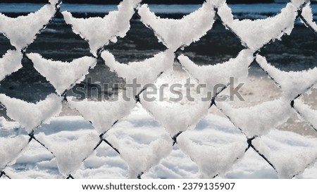 Close-up of snow accumulated on the chain fence on a snowy winter day. Textural effect, background