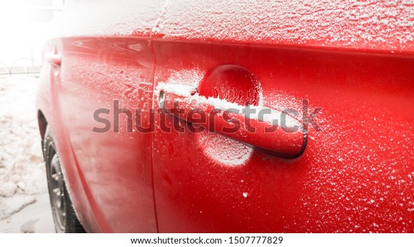 Closeup of snow covered car with frozen door and\
door lock