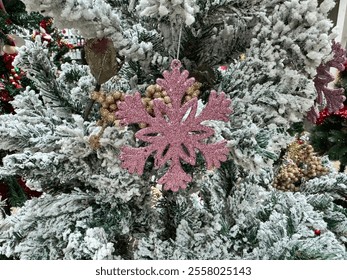 Close-up of a snowy pine tree with a pink sparkling snowflake hanging on a pine branch. - Powered by Shutterstock