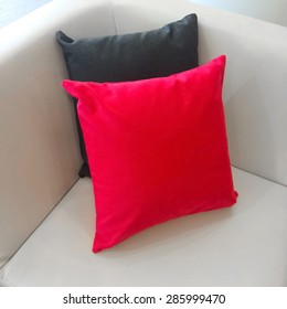 Close-up of sofa corner with red and gray cushions.