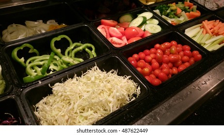 Close-up, soft focus salad bar with various fresh vegetables and fruits. Colorful organic raw slice lettuce, carrot, cucumber, pecan, blueberries, strawberries, grape, dressing. Healthy diet eating