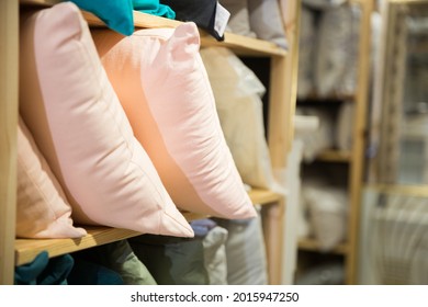Closeup of soft pillows for sale on shelving in home furnishings store. Showcase with bedding
