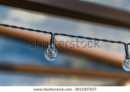 Close-up of a solar-powered LED string light designed for decorative outdoor garden lighting. The energy-efficient LED bulb is mounted on a weather-resistant cable, providing ambient illumination for patios, pergolas, terraces, balconies, and backyard spaces. Ideal for concepts related to sustainable energy, outdoor decoration, and modern garden design.