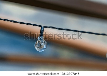 Close-up of a solar-powered LED string light designed for decorative outdoor garden lighting. The energy-efficient LED bulb is mounted on a weather-resistant cable, providing ambient illumination for patios, pergolas, terraces, balconies, and backyard spaces. Ideal for concepts related to sustainable energy, outdoor decoration, and modern garden design.