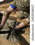 Close-up of a soldier applying a tourniquet on an injured limb during training