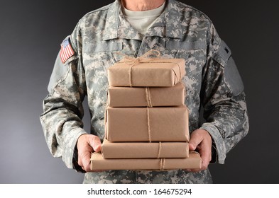 Closeup Of A Soldier Wearing Camouflage Fatigues Holding A Stack Of Packages For Mail Call. Horizontal Format, Man Is Unrecognizable.