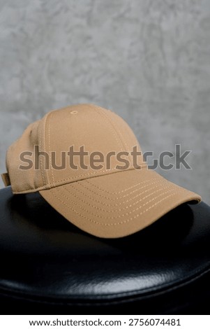 Close-up of a solid sand-colored baseball cap. Front view of a beige cap with a curved visor on a black surface