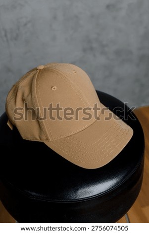 Close-up of a solid sand-colored baseball cap. Front view of a beige cap with a curved visor on a black surface