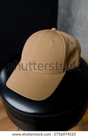 Close-up of a solid sand-colored baseball cap. Front view of a beige cap with a curved visor on a black surface